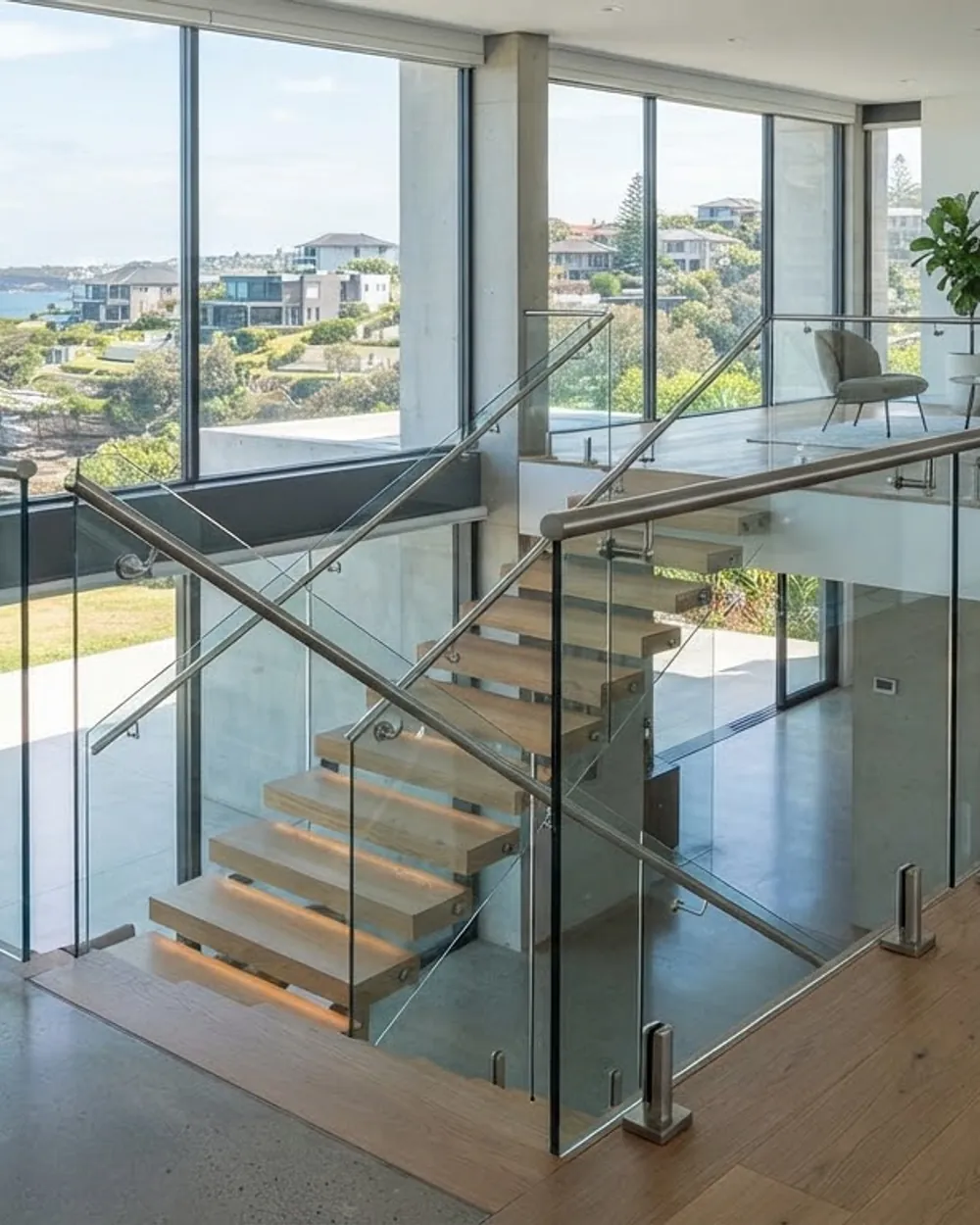Frameless glass balustrade enclosing an interior landing above a timber stair.